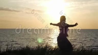 一个年轻的女孩正在<strong>草地</strong>上，在夕阳和<strong>大海</strong>的背景下旋转，享受着阳光。 4k，3840x2160